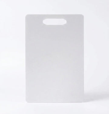 Flat white plastic cutting board with built in top handle hole on plain background