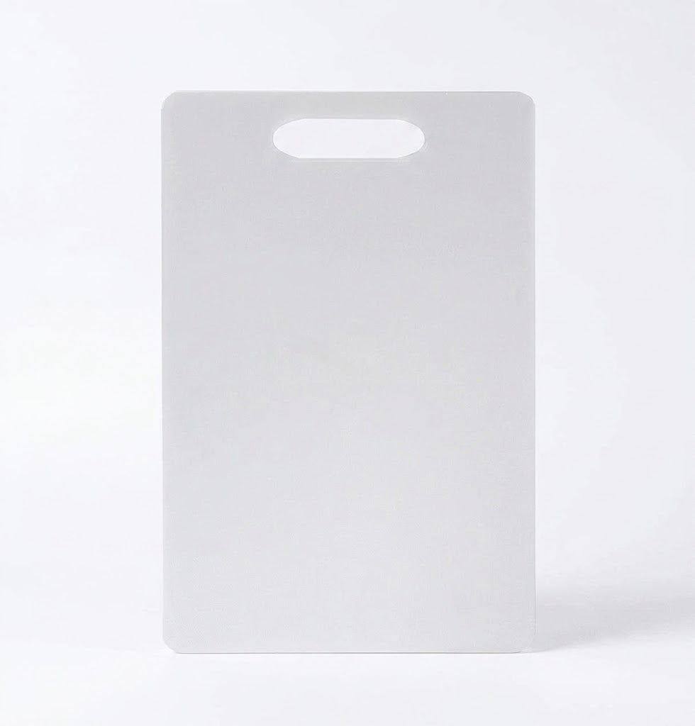 Flat white plastic cutting board with built in top handle hole on plain background