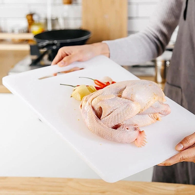 Person holding a white plastic chopping board with a whole raw chicken and ingredients